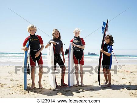 Picture - Children standing with surfboards on the beach, front view . Fotosearch