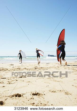 Children with surfboards running into the water, rear view View Large Photo Image Stock Photograph - Children with surfboards running into the water, rear view . Fotosearch