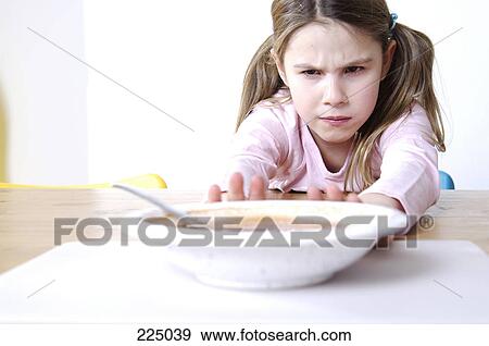 Stock Photo - Close-up of a girl pushing a plate of soup on the table . Fotosearch