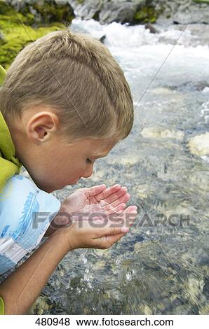 Close-up of boy drinking water from river View Large Photo Image Stock Photo - Close-up of boy drinking water from river . Fotosearch