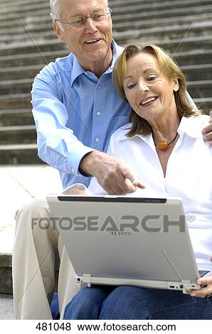 Close-up of couple looking at laptop and smiling View Large Photo Image Stock Photo - Close-up of couple looking at laptop and smiling . Fotosearch