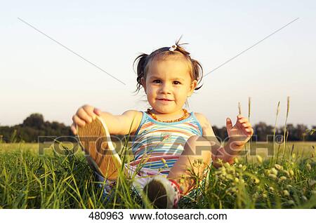 Stock Image - Close-up of girl sitting in field . Fotosearch