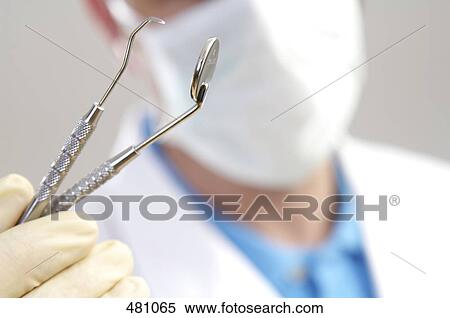Stock Photography - Close-up of male dentist holding plaque remover . Fotosearch