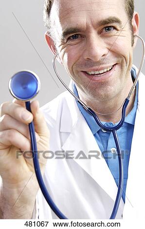 Stock Photo - Close-up of male doctor holding stethoscope and smiling . Fotosearch
