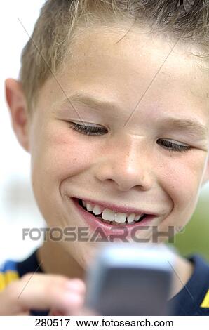 Close-up of teenage boy using mobile phone and smiling View Large Photo Image Stock Photo - Close-up of teenage boy using mobile phone and smiling . Fotosearch