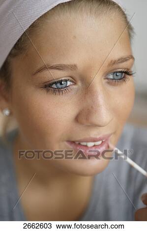 Close-up of teenage girl applying lip gloss View Large Photo Image Stock Image - Close-up of teenage girl applying lip gloss . Fotosearch