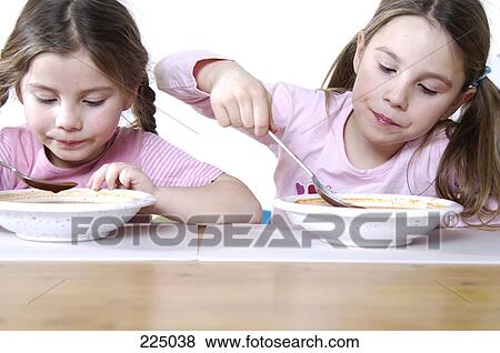 Stock Photo - Close-up of two girls eating breakfast . Fotosearch