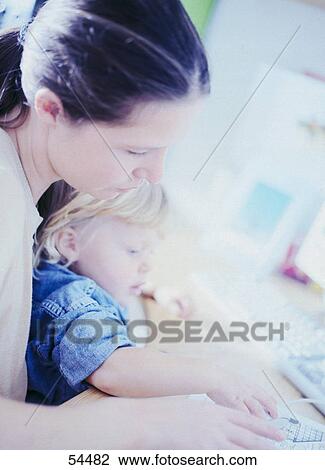 Stock Image - Close-up of woman working on computer with her child . Fotosearch
