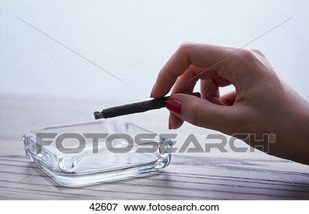 Stock Photo - Close-up of woman's hand holding cigar over ashtray . Fotosearch