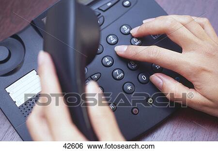 Stock Photograph - Close-up of woman's hands dialing landline phone . Fotosearch