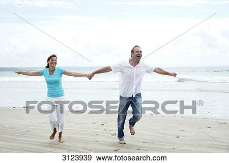 Stock Photo - Couple running on a beach, front view . Fotosearch