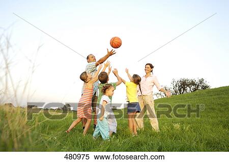 Stock Photography - Family playing basketball in field . Fotosearch