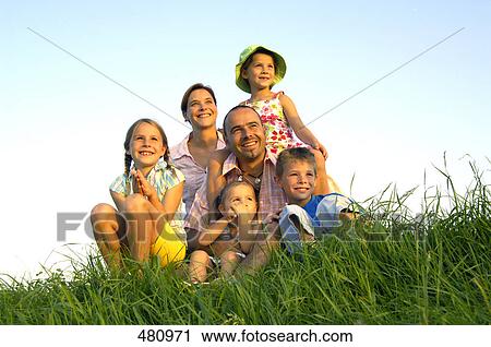 Stock Image - Family sitting in field . Fotosearch