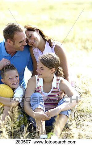 Stock Photo - Family sitting in field . Fotosearch