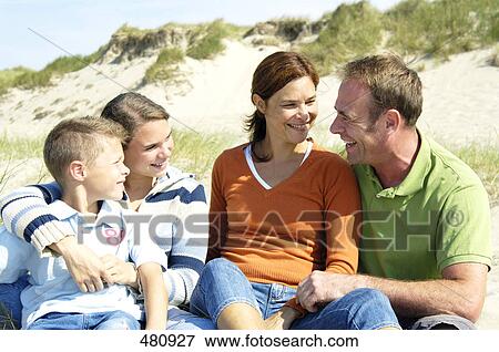 Stock Photo - Family sitting on beach and smiling . Fotosearch