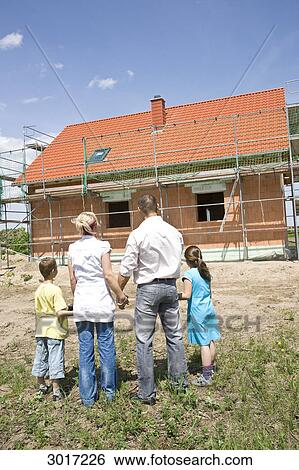Family with two children looking at house under construction, rear view View Large Photo Image Stock Photograph - Family with two children looking at house under construction, rear view . Fotosearch