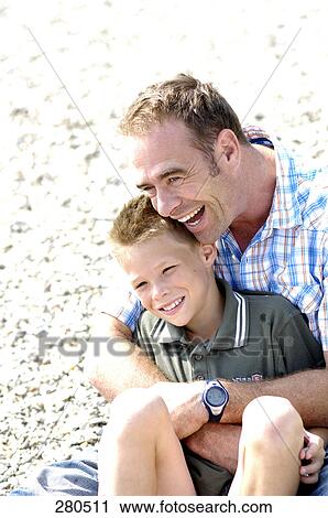 Stock Image - Father and his son smiling in field . Fotosearch
