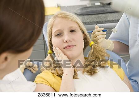 Stock Image - Female dentist and assistant examining patient . Fotosearch