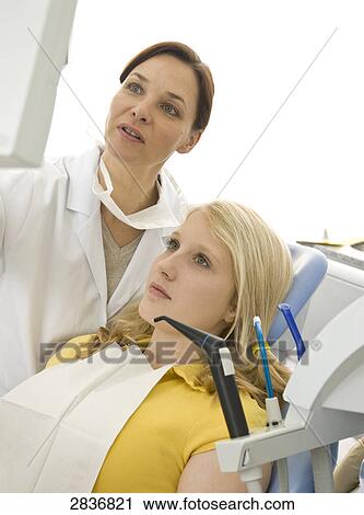 Stock Image - Female dentist and patient looking at monitor . Fotosearch