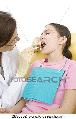 Stock Image - Female dentist examining patient's teeth . Fotosearch