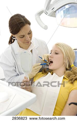 Stock Image - Female dentist examining patient's teeth . Fotosearch