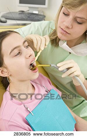 Stock Photography - Female dentist examining patient's teeth . Fotosearch