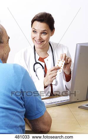 Stock Image - Female doctor showing medicine to patient . Fotosearch
