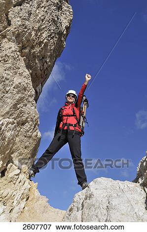 Stock Photo - Female hiker celebrating while standing on rock, Trentino-Alto Adige, Italy . Fotosearch