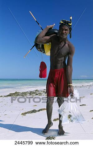Stock Photo - Fisherman carrying diving gears on beach, Diani Beach, Kenya . Fotosearch