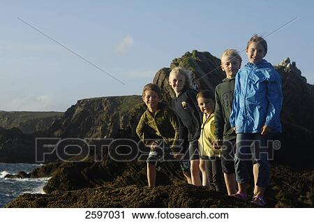 Stock Image - Five children standing at coast and smiling . Fotosearch