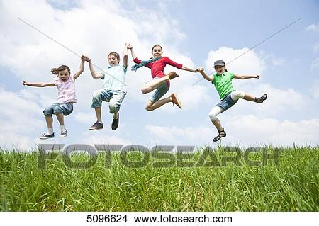 Four children jumping hand in hand in meadow View Large Photo Image Picture - Four children jumping hand in hand in meadow . Fotosearch