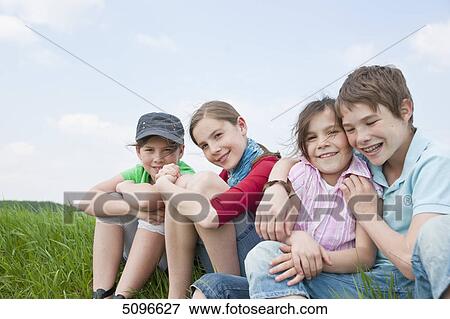 Four children sitting in meadow View Large Photo Image Stock Photo - Four children sitting in meadow . Fotosearch