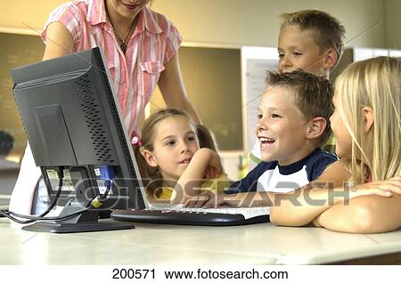 Stock Image - Four students and teacher looking at computer monitor . Fotosearch