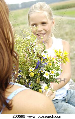 Girl giving bouquet of flowers to her mother View Large Photo Image Stock Photography - Girl giving bouquet of flowers to her mother . Fotosearch