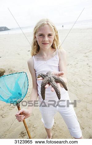 Stock Photography - Girl holding a starfish into the camera . Fotosearch