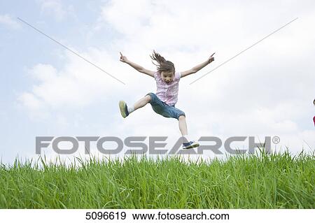 Girl jumping in meadow View Large Photo Image Stock Photo - Girl jumping in meadow . Fotosearch