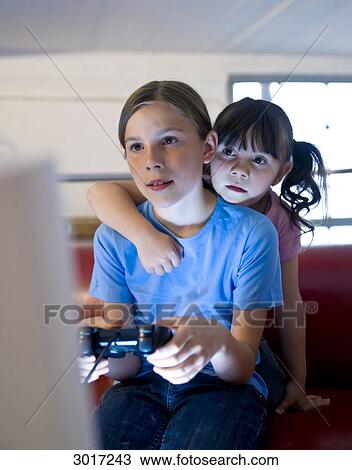 Girl playing a computer game while her sister is watching her View Large Photo Image Stock Image - Girl playing a computer game while her sister is watching her . Fotosearch