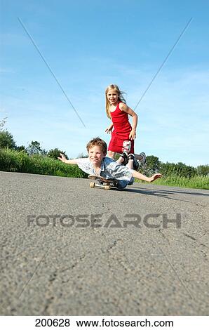 Girl pushing her brother on a skateboard View Large Photo Image Stock Photo - Girl pushing her brother on a skateboard . Fotosearch