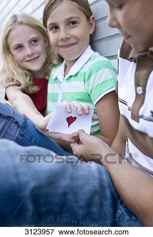 Girl showing boy a card with a heart on it, low angle view View Large Photo Image Stock Photo - Girl showing boy a card with a heart on it, low angle view . Fotosearch