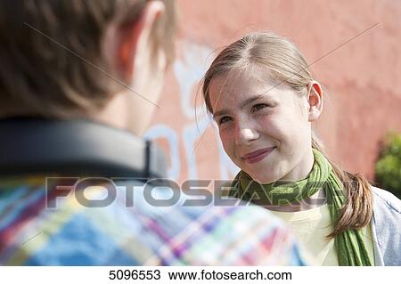 Stock Image - Girl smiling at boy with headphones . Fotosearch