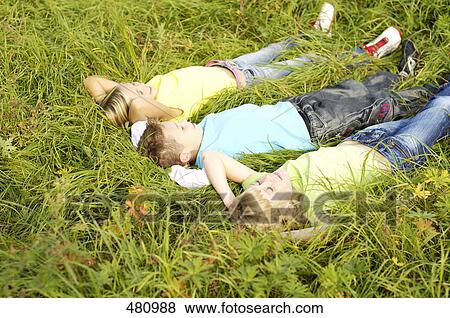 High angle view of brother and sisters lying on grass View Large Photo Image Stock Photo - High angle view of brother and sisters lying on grass . Fotosearch