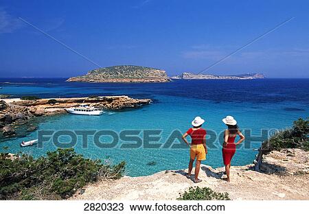 Stock Image - High angle view of tourists standing on cliff, Cala Comte, Ibiza, Balearic Islands, Spain . Fotosearch
