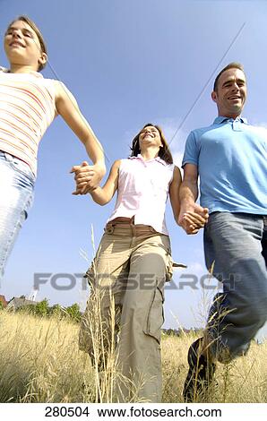 Picture - Low angle view of family walking in field . Fotosearch