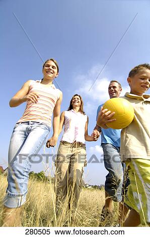 Stock Photography - Low angle view of family walking in field . Fotosearch