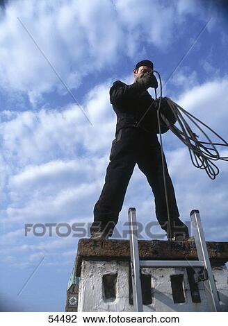 Low angle view of man cleaning chimney at top of building View Large Photo Image Stock Image - Low angle view of man cleaning chimney at top of building . Fotosearch