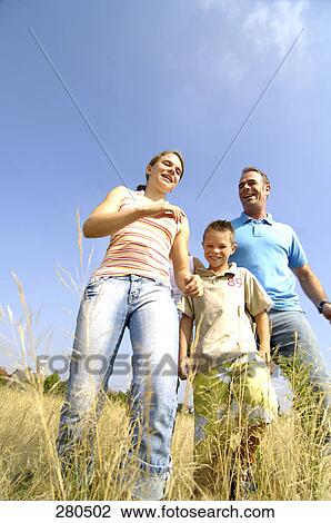 Low angle view of man walking with his daughter and son on a field View Large Photo Image Stock Image - Low angle view of man walking with his daughter and son on a field . Fotosearch