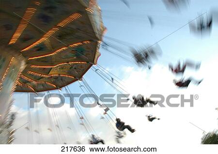Low angle view of people riding on chain swing ride View Large Photo Image Stock Photograph - Low angle view of people riding on chain swing ride . Fotosearch