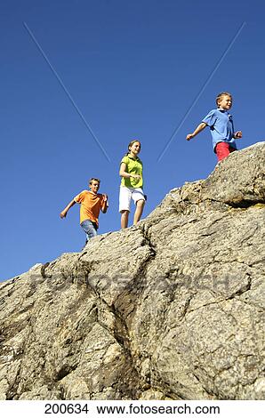 Low angle view of three children walking on cliff View Large Photo Image Picture - Low angle view of three children walking on cliff . Fotosearch