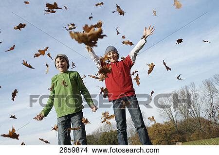 Low angle view of two boys throwing dry leaves View Large Photo Image Picture - Low angle view of two boys throwing dry leaves . Fotosearch