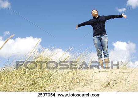 Low angle view of young woman stretching her arms on beach View Large Photo Image Picture - Low angle view of young woman stretching her arms on beach . Fotosearch